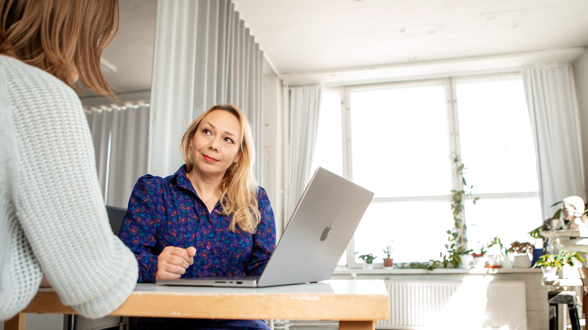 Noon Kollektiivin someviestinnän asiantuntija Anu Dufva sparraa asiakasta tietokoneen ääressä.